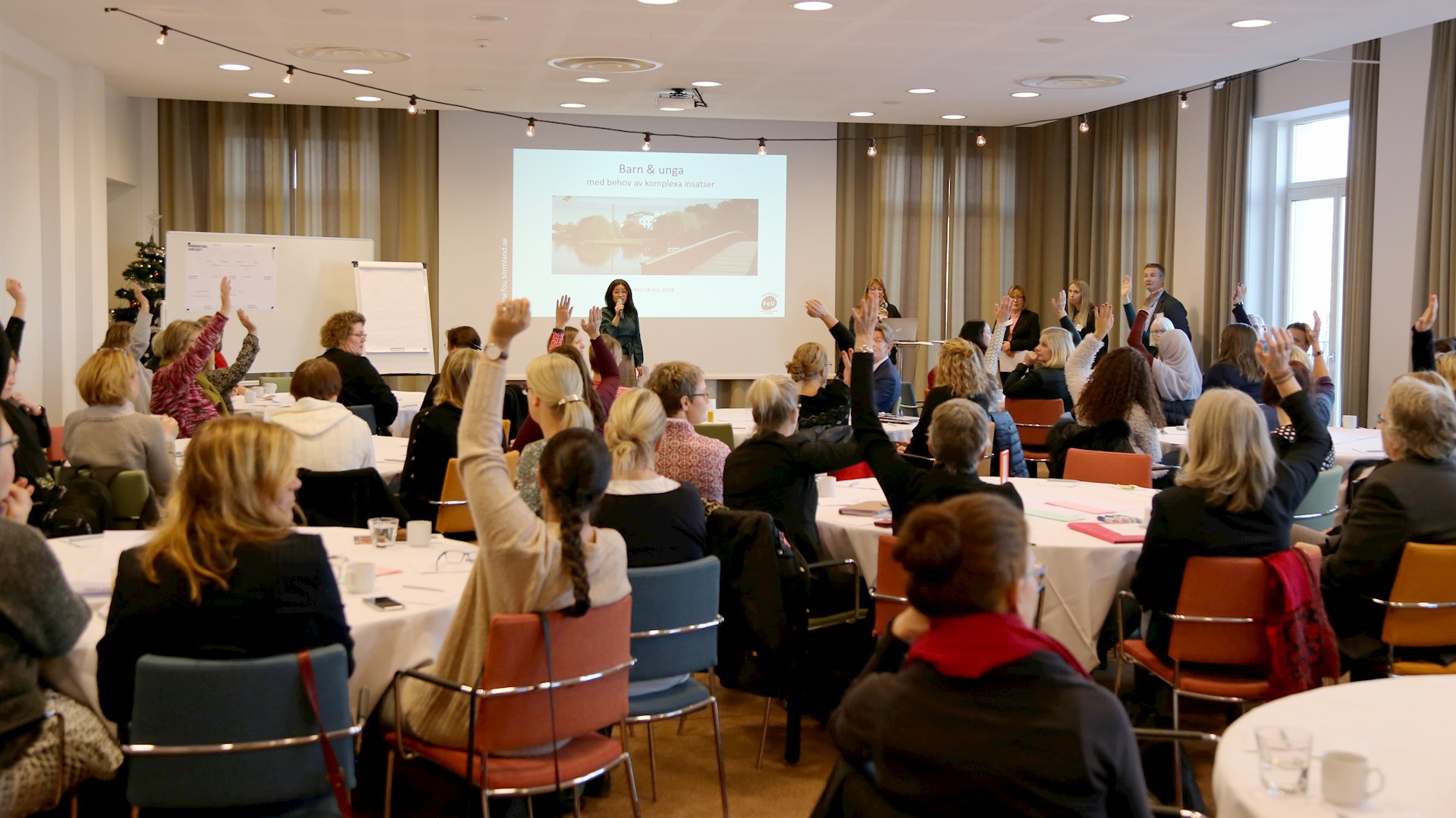 Föreläsning där deltagare räcker upp handen