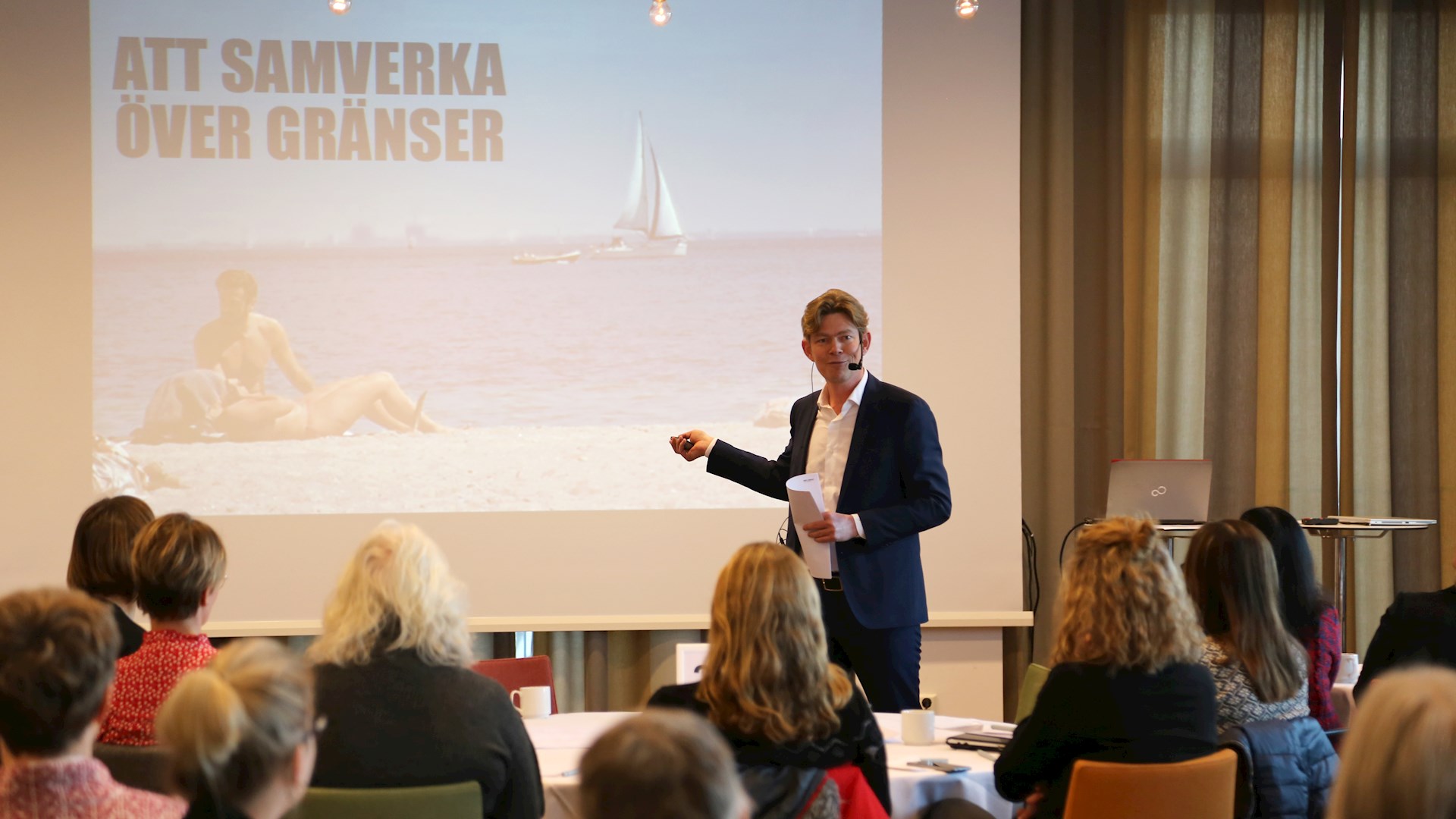 Jesper Henriksen framför en presentation med texten "att samverka över gränser"