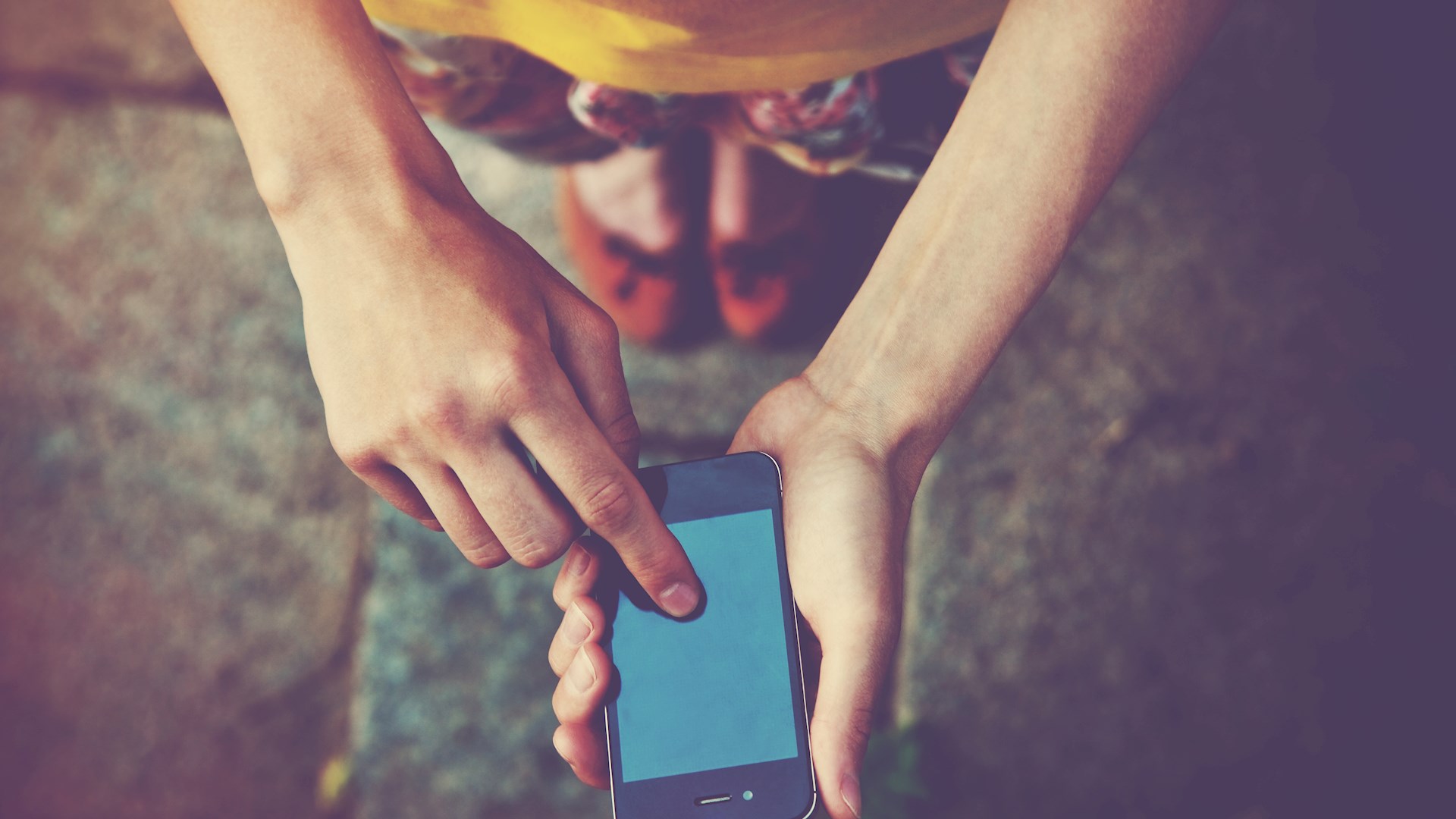En person som pekar på sin mobiltelefon, uppifrån