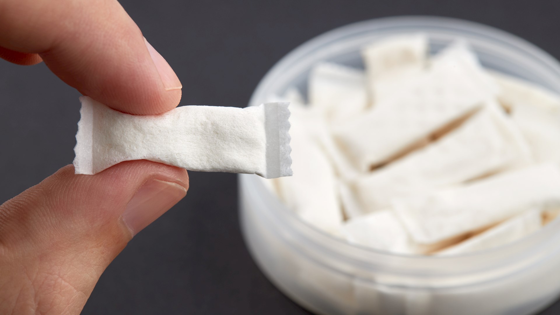 En dosa vitt snus och en hand som håller en snus, bild från Adobe Stock