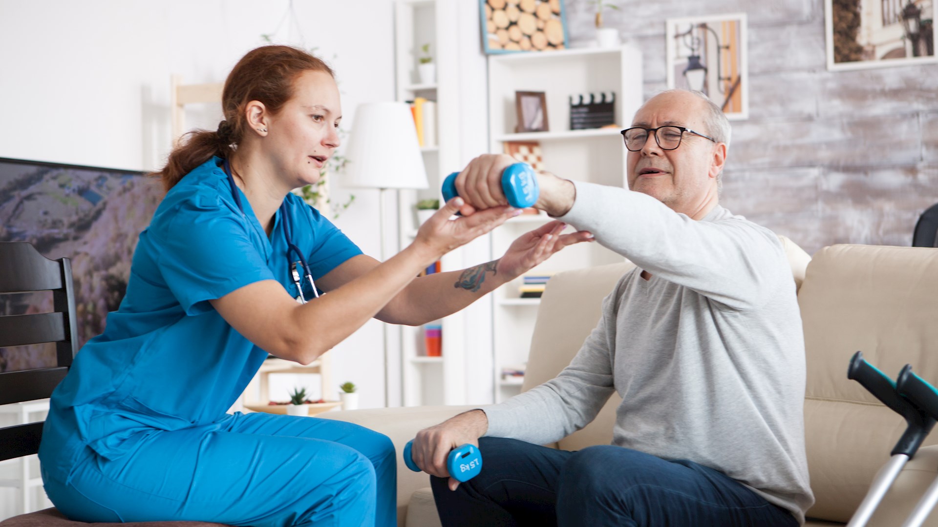 En vårdpersonal hjälper en man med rehabilitiering  i hemmet, från Adobe stock