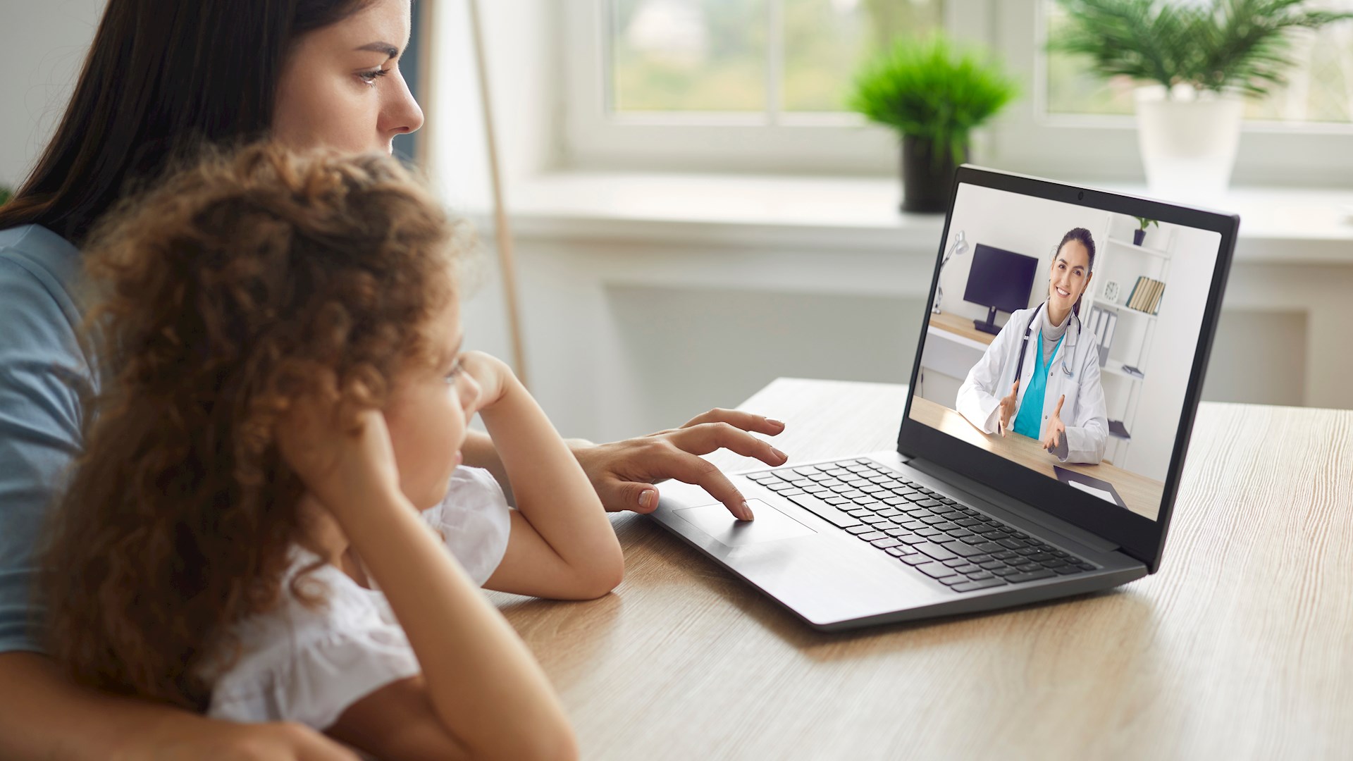 En kvinna och en flicka i digitalt möte med en vårdpersonal från Adobe Stock