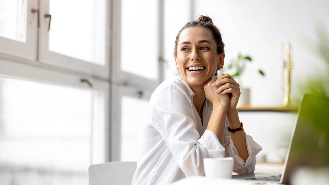Adobe Stock_kvinna ser nöjd ut på sitt kontor